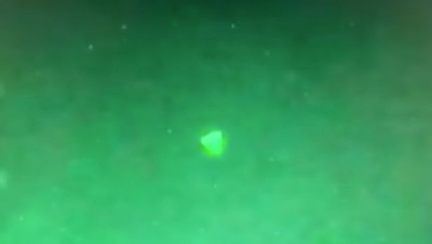 На видео виден треугольный объект, парящий высоко над военным кораблем.