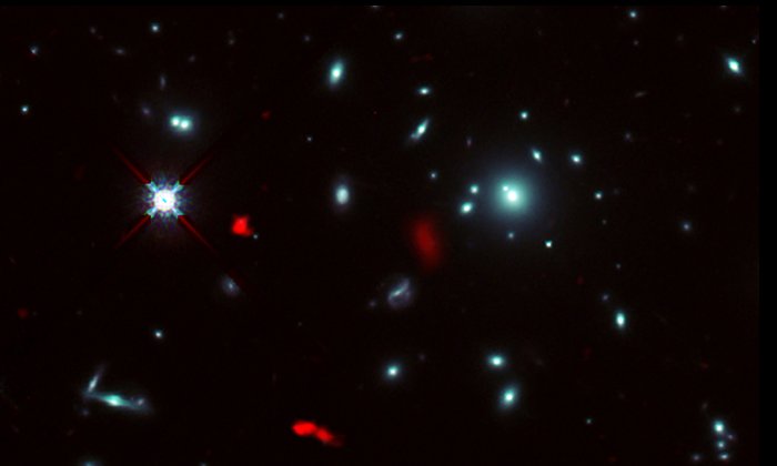Скопление галактик RXCJ0600-2007, полученное космическим телескопом Хаббла НАСА / ЕКА, в сочетании с изображениями, полученными методом гравитационного линзирования, далекой галактики RXCJ0600-z6, удаленной от нас на 12,4 миллиарда световых лет и наблюдаемой ALMA (показано красным). Из-за эффекта гравитационного линзирования скоплением галактик изображение RXCJ0600-z6 было усилено и увеличено, и казалось, что оно разделено на три или более частей. Авторы и права: ALMA (ESO / NAOJ / NRAO), Fujimoto и др., Космический телескоп Хаббла НАСА / ЕКА.