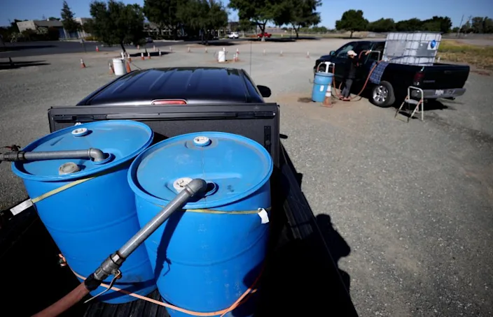 Житель наполняет резервуар для воды оборотной водой с заправочной станции в Окли.