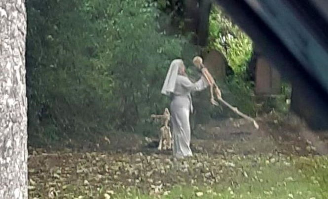 Монахиня танцует со скелетами рядом с кладбищем