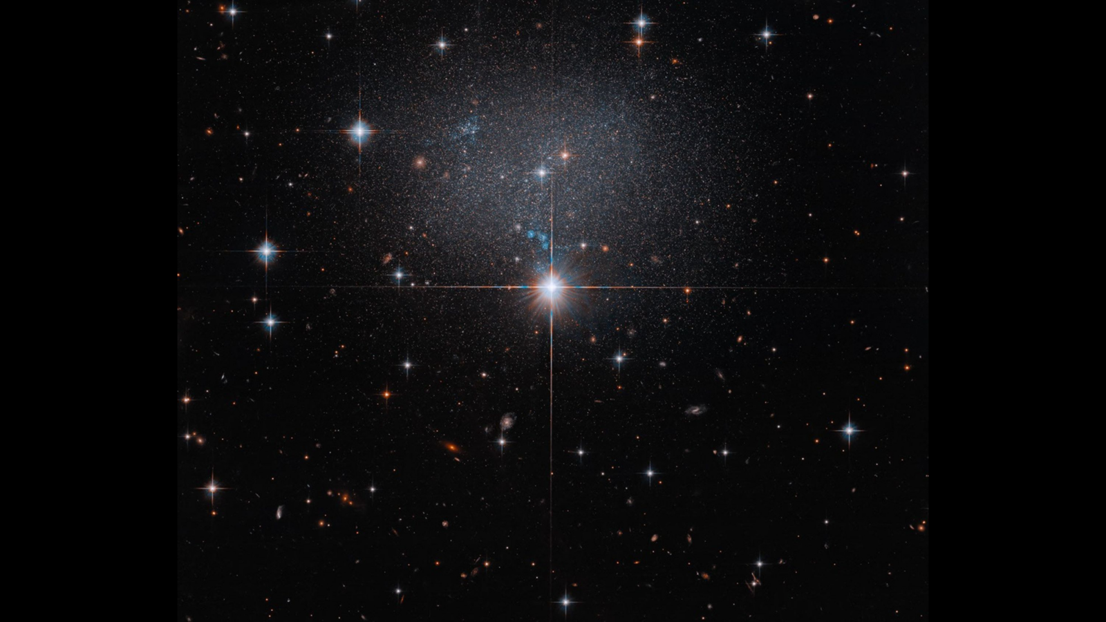 Крошечная галактика в Большом Псе: Hubble запечатлел редкий «неправильный» космический бриллиант
